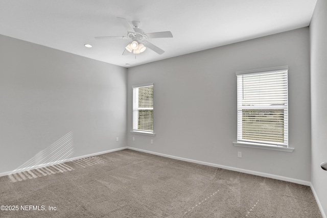 carpeted spare room featuring plenty of natural light and ceiling fan