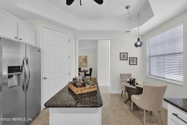 kitchen featuring decorative light fixtures, a raised ceiling, stainless steel fridge, white cabinetry, and ceiling fan