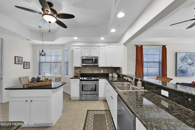 kitchen with appliances with stainless steel finishes, white cabinets, a raised ceiling, and sink