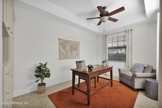 home office featuring ceiling fan, light tile patterned flooring, and a tray ceiling