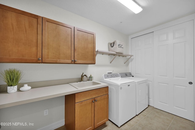 washroom featuring a textured ceiling, washing machine and dryer, light tile patterned floors, cabinets, and sink