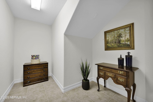 corridor with lofted ceiling and light tile patterned flooring