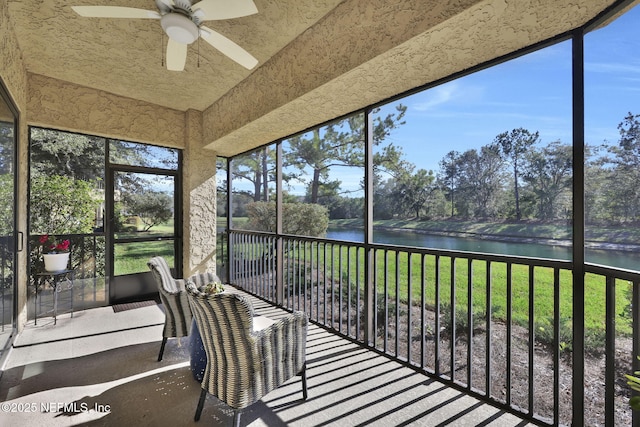 unfurnished sunroom with ceiling fan, a wealth of natural light, and a water view