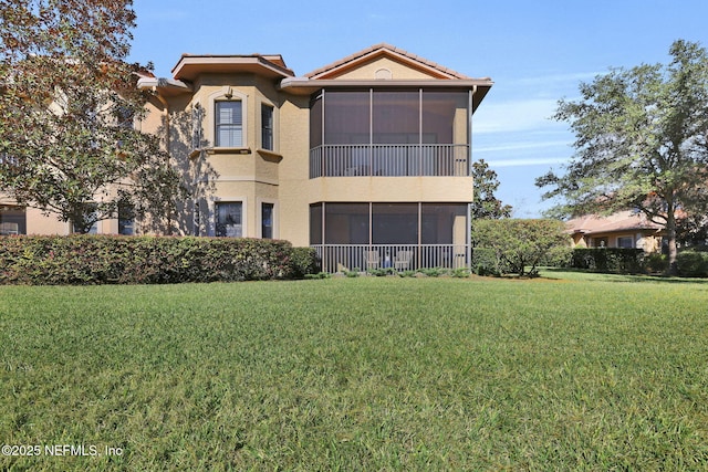 back of property with a yard and a sunroom