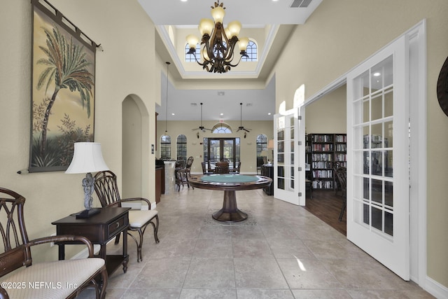 tiled entrance foyer with a towering ceiling, french doors, a chandelier, and crown molding