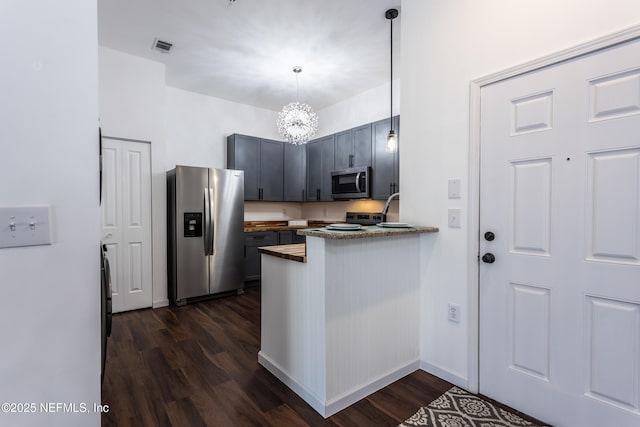 kitchen featuring wood counters, an inviting chandelier, hanging light fixtures, dark hardwood / wood-style floors, and stainless steel appliances