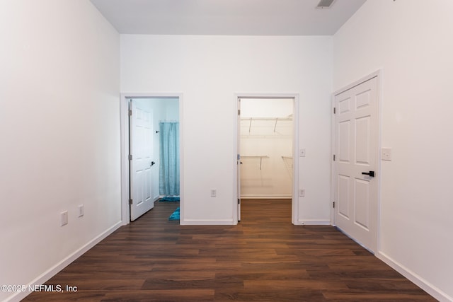 unfurnished bedroom featuring dark hardwood / wood-style flooring, ensuite bathroom, a spacious closet, and a closet