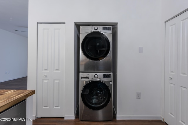 clothes washing area featuring dark hardwood / wood-style flooring and stacked washer / drying machine