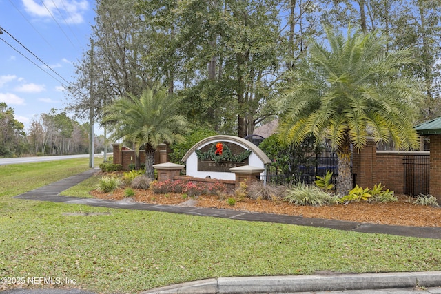 community / neighborhood sign featuring a yard and fence