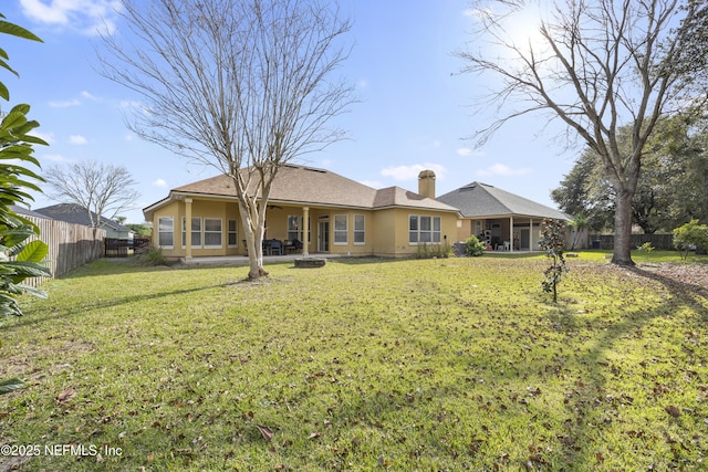 rear view of property featuring a yard, a chimney, a patio, stucco siding, and a fenced backyard