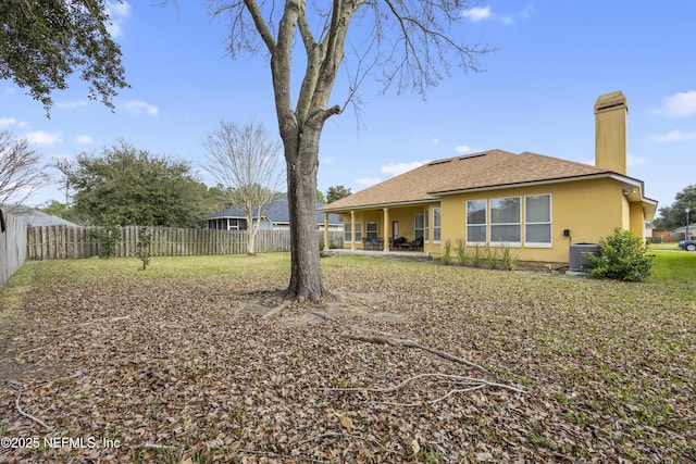 back of house with a fenced backyard, roof with shingles, a chimney, and stucco siding