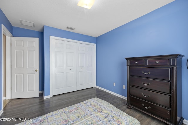 bedroom featuring baseboards, visible vents, dark wood finished floors, and a closet