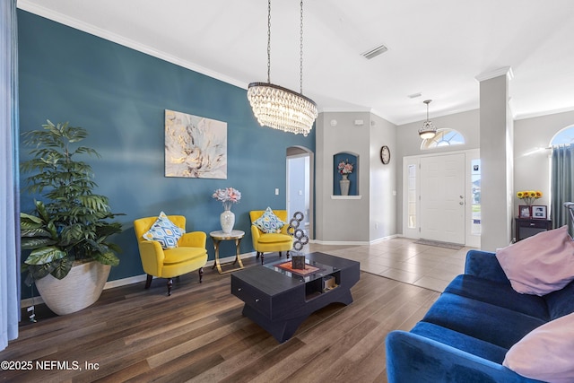 living room with baseboards, visible vents, wood finished floors, and ornamental molding