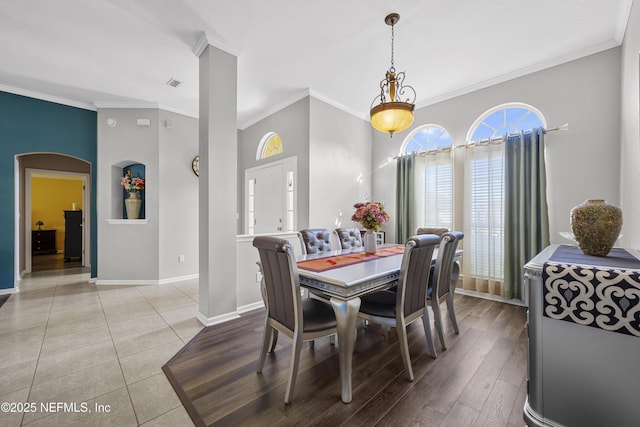 dining space featuring arched walkways, baseboards, visible vents, and crown molding