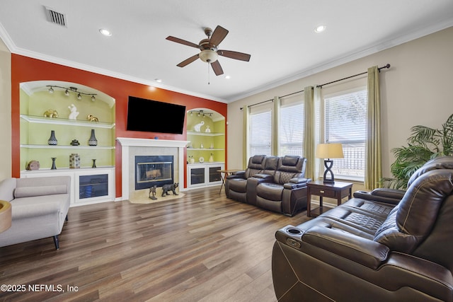 living room featuring ornamental molding, visible vents, a fireplace, and wood finished floors