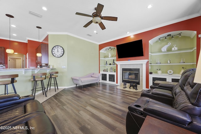 living area featuring crown molding, built in features, wood finished floors, and a tile fireplace