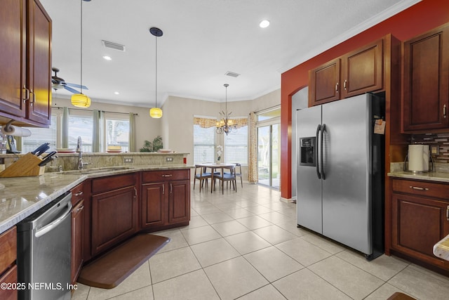 kitchen with light stone counters, pendant lighting, stainless steel appliances, visible vents, and ornamental molding