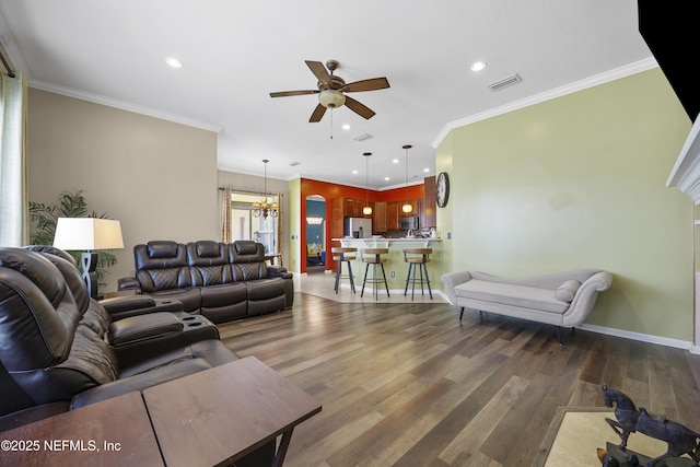 living area with crown molding, visible vents, wood finished floors, and ceiling fan with notable chandelier