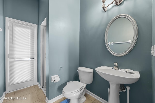 bathroom with toilet, baseboards, and tile patterned floors