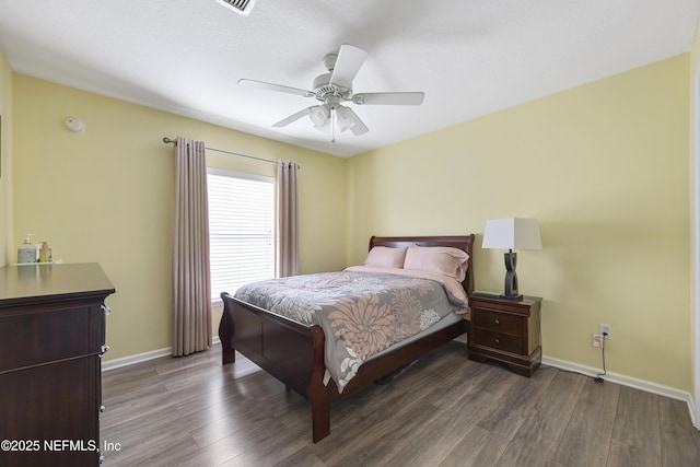 bedroom featuring dark wood-style flooring, a ceiling fan, and baseboards