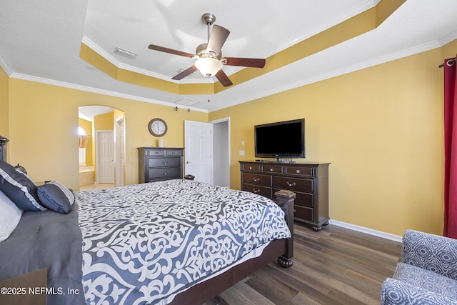 bedroom with baseboards, visible vents, arched walkways, dark wood-style flooring, and a tray ceiling