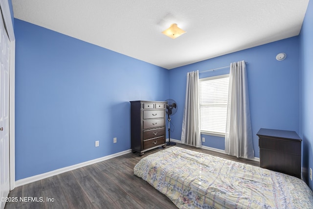 bedroom with a textured ceiling, baseboards, and dark wood-style flooring