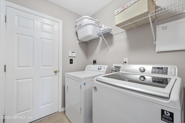 washroom featuring laundry area, washing machine and clothes dryer, and light tile patterned floors