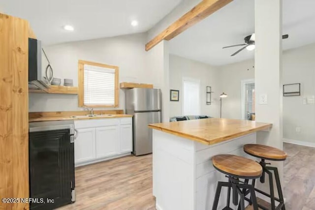 kitchen with a breakfast bar, ceiling fan, light wood-type flooring, white cabinetry, and stainless steel refrigerator