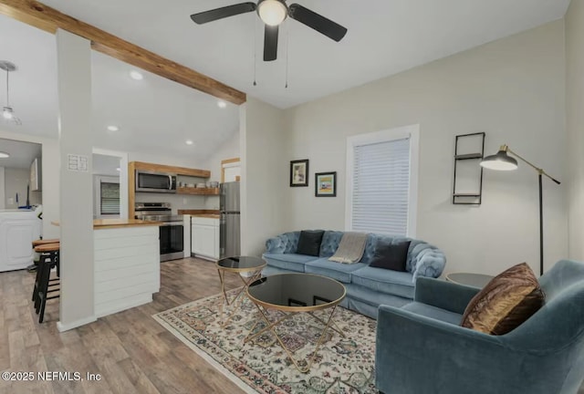 living room featuring washer / dryer, vaulted ceiling with beams, light hardwood / wood-style floors, and ceiling fan