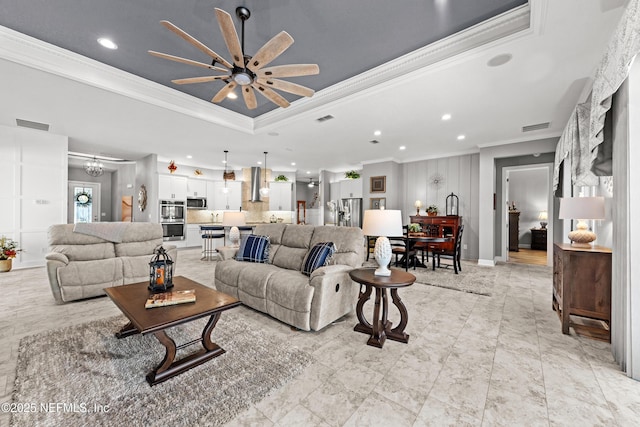 living room featuring a raised ceiling, ceiling fan, and ornamental molding