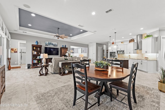 dining room featuring ceiling fan, a raised ceiling, and ornamental molding