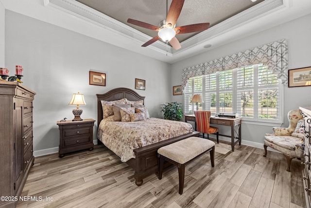 bedroom with a tray ceiling, ceiling fan, and light hardwood / wood-style floors