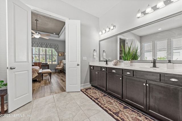 bathroom featuring tile patterned floors, vanity, a raised ceiling, ceiling fan, and crown molding