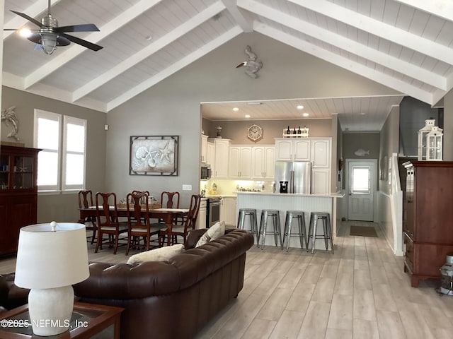 living room featuring beam ceiling, light hardwood / wood-style floors, high vaulted ceiling, and ceiling fan