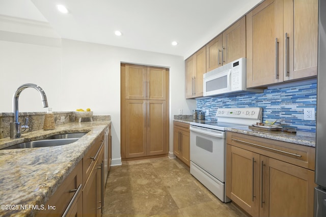 kitchen with backsplash, light stone counters, sink, and white appliances