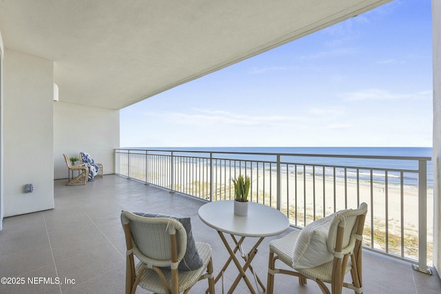 balcony featuring a view of the beach and a water view