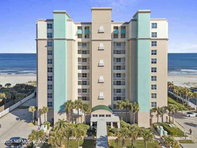 view of building exterior featuring a beach view and a water view