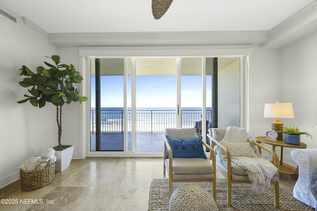 living area with a water view and crown molding