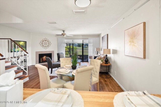 living room with a fireplace, wood-type flooring, a textured ceiling, and ceiling fan