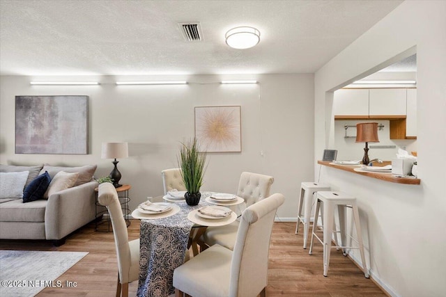 dining space featuring a textured ceiling and light wood-type flooring