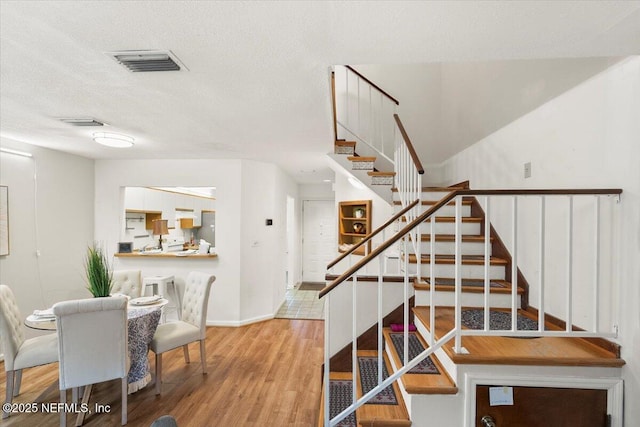 stairs featuring hardwood / wood-style flooring and a textured ceiling