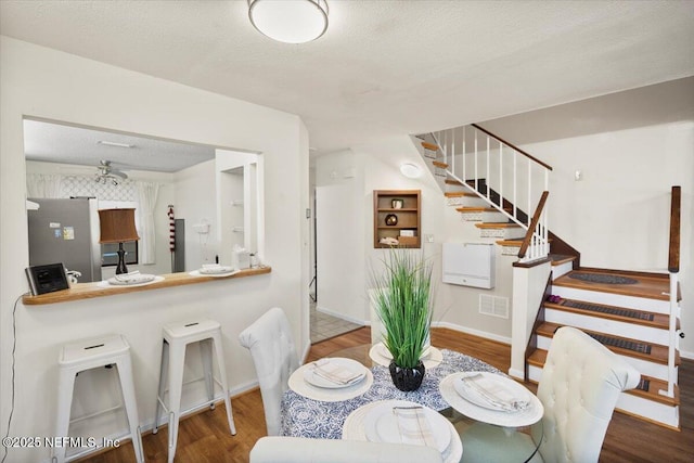 dining space featuring hardwood / wood-style flooring, ceiling fan, and a textured ceiling