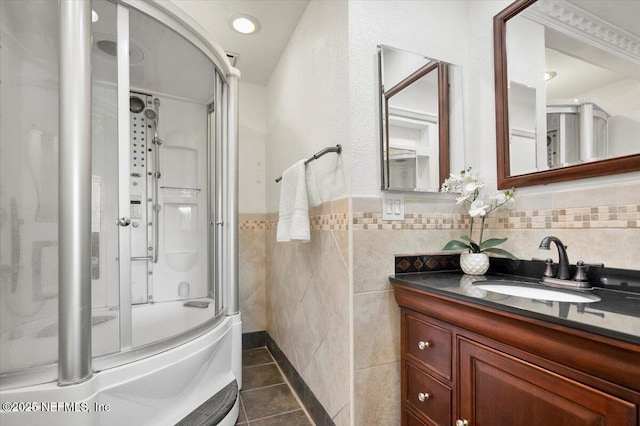 bathroom featuring tile patterned floors, vanity, enclosed tub / shower combo, and tile walls