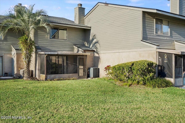 back of house with a sunroom, a yard, and central AC