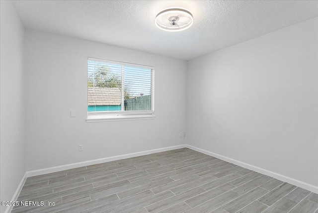 spare room with wood tiled floor, a textured ceiling, and baseboards