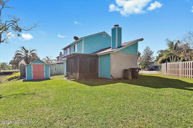 back of property with a storage shed, a sunroom, an outbuilding, fence, and a yard