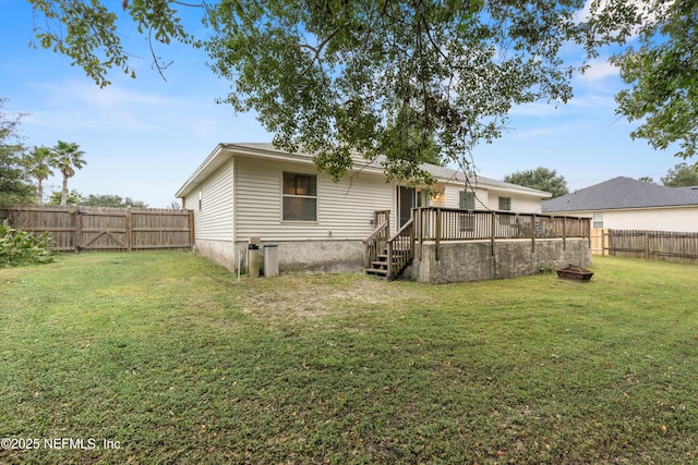 back of house featuring a lawn and a deck