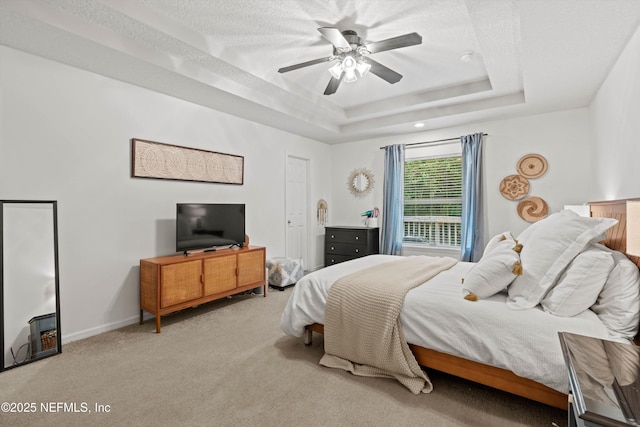 bedroom with a tray ceiling, ceiling fan, light colored carpet, and a textured ceiling