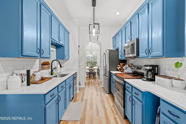 kitchen with blue cabinetry, pendant lighting, and stainless steel appliances