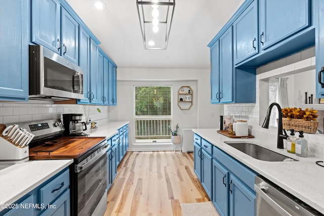 kitchen featuring blue cabinetry, appliances with stainless steel finishes, and sink